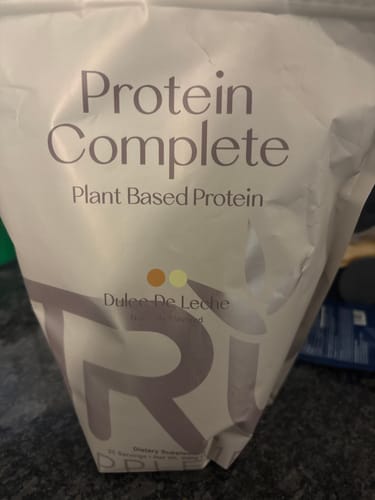 Customer's white bag of Protein Complete plant-based protein powder on a countertop.