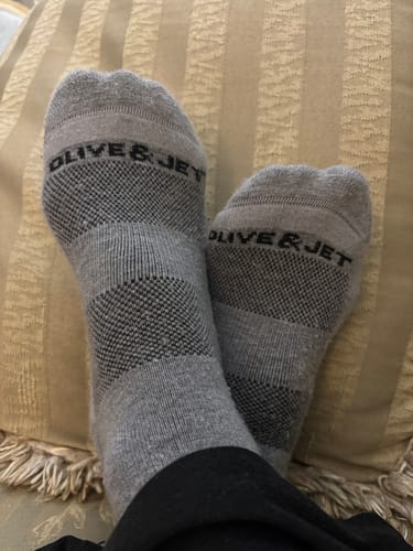 Reviewer's feet wearing the grey Quarter Socks, crossed at the ankles while resting on a pillow.