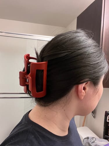 Reviewer with thick, dark hair held up securely in a messy bun by a red cloud clip.
