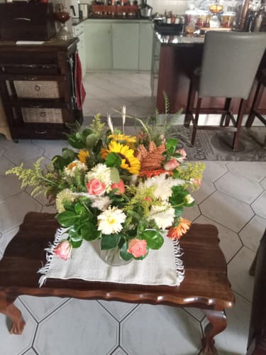 Customer's large Sunshine Sunflower Flower Arrangement with mixed flowers on a wooden coffee table in a home.