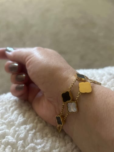 Customer's wrist showing a lovely gold-tone bracelet with black and white clover charms from the clearance sale.