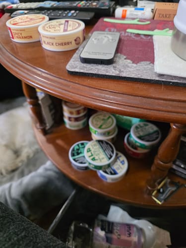 Customer's collection of various ALP nicotine pouches, including Refreshing Chill, stored on a wooden end table.
