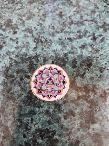 Reviewer's 30 Year Sobriety Mint featuring a bright, colorful lotus flower design, resting on a counter.