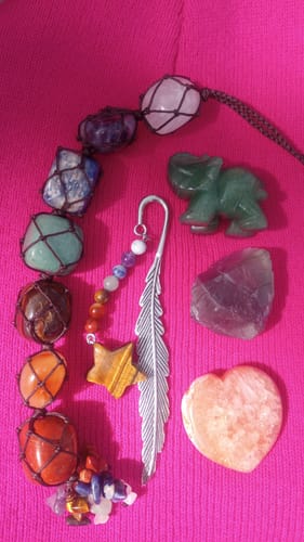 Reviewer's collection from their AuraBloom Subscription Box, showing colorful crystals, a figurine, and a feather bookmark.