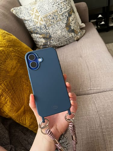 Cliente segurando a case Azul da Cor do Mar em um celular, mostrando a alça conectada.