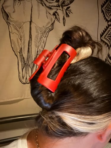 Customer wearing the red cloud clip, which holds their dark and blonde hair up in a bun.