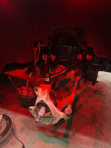 Close-up of a reviewer's new black Front Upper Control Arm installed on a truck's front suspension assembly.