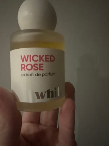 Close-up of a reviewer holding the Wicked Rose extrait de parfum bottle.