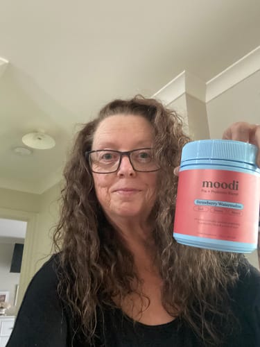 Reviewer holding the Strawberry Watermelon Pre + Probiotic Blend product container in their kitchen.
