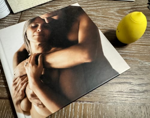 Customer's yellow Lem Clitoral Massager on a wooden table next to a book.