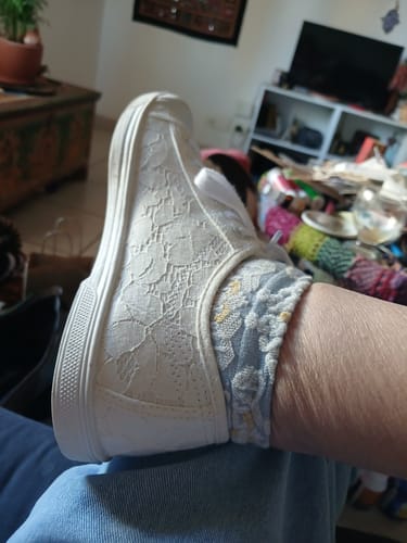 Close-up of a reviewer wearing a casual floral sock with a white lace sneaker.