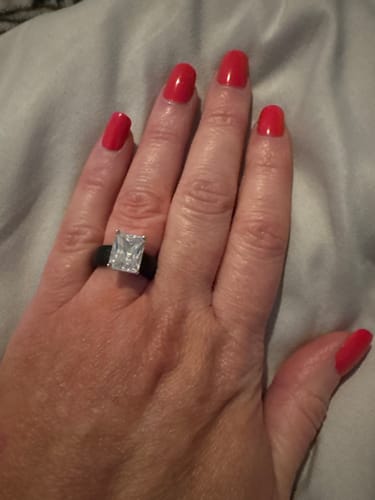 Reviewer's hand wearing the Silicone Ring, which has a black band and a large, rectangular emerald-cut stone.