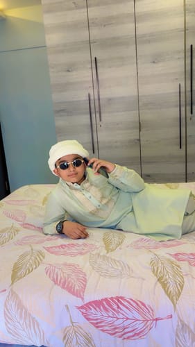 Reviewer wearing the Golden Oval Sunglasses while posing on a bed.