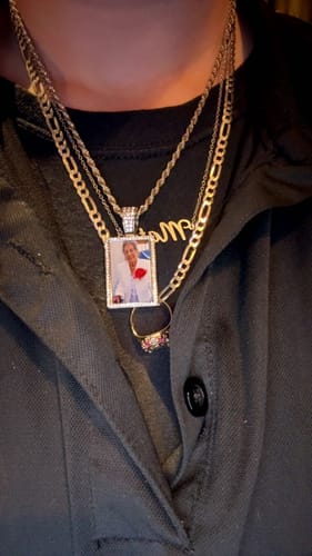 Customer wearing the personalized photo necklace with a diamond-studded border, layered with other silver-tone chains.