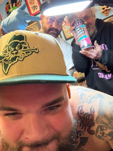 Customer taking a selfie in a tattoo studio, showing his tattooed back and shoulder.