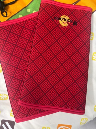 Customer's pair of red Dragonforged Knee Sleeves with a geometric pattern laid out on a bed.