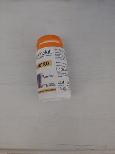 Recensore mostra il flacone bianco dell'integratore Artro su una superficie chiara.
