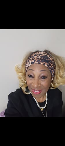 Customer wearing the wavy, blonde Shake N Go Harmony wig, styled with a leopard print headband.