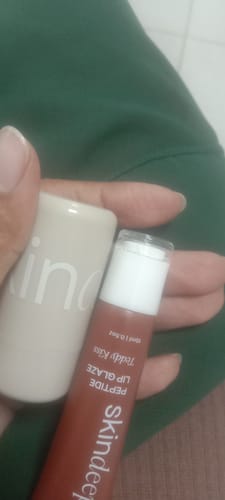 Customer holding the Lip Glaze tube and the Velvet Flush container from the duo set.
