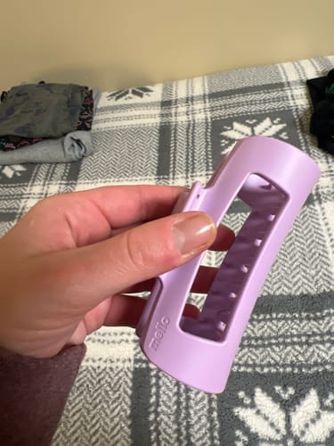 Customer's hand holding a light purple cloud clip over a patterned blanket.