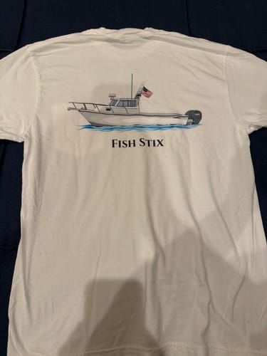 Customer's white t-shirt featuring their custom boat artwork of a boat named 'FISH STIX' with an American flag.
