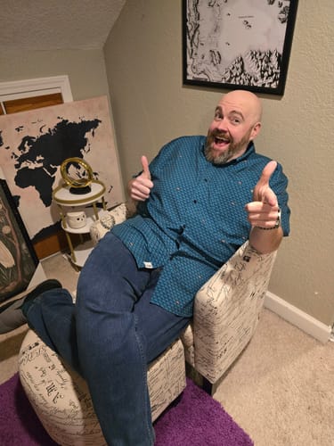 Reviewer smiling and pointing while wearing the teal Wee Cows – KUNUFLEX Short Sleeve Shirt.