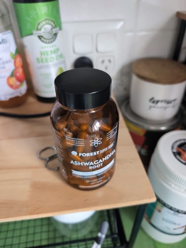Customer's bottle of Organic Ashwagandha Capsules on a wooden kitchen shelf among other pantry items.
