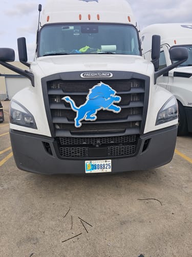 Customer's blue Detroit Lions metal art mounted on the front grille of a large white truck.