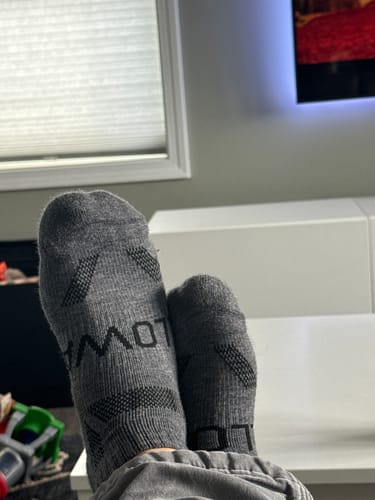 Customer relaxing with their feet up, wearing the grey Men's Alpaca Socks indoors.