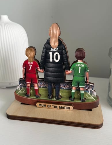 Customer's 'Mum Of The Match' wooden plaque showing the back of a person and two children in personalized football kits.