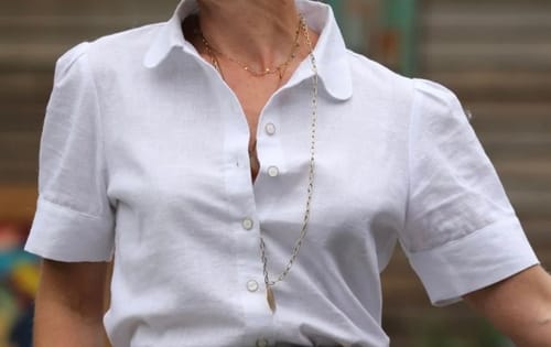 Gros plan sur la blouse Amandine en lin blanc cassé portée par une cliente, qui montre le col et les manches courtes.