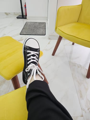 Cliente con el zapato barefoot Roam I negro puesto en el pie, descansando sobre un mueble amarillo.