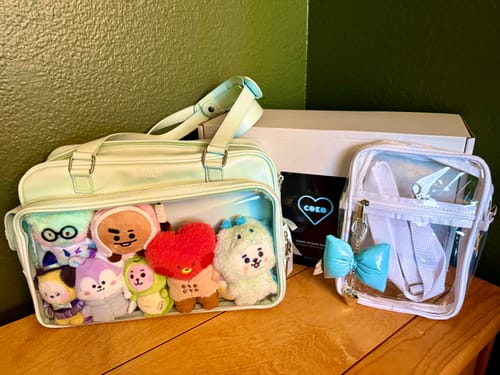 Customer's light blue COKO STAGE BAG with its clear front pocket filled with plushies, next to a smaller clear pouch with a bow.
