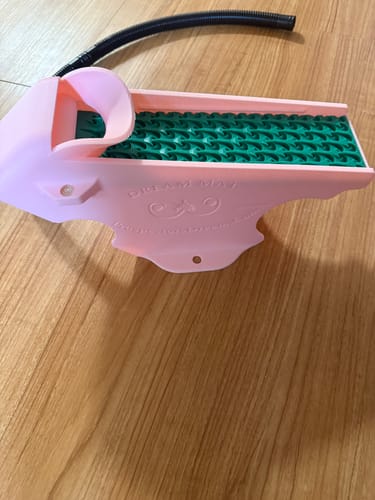 Customer's pink Gold Clean Up Buddy with a green mat, shown from the side on a wooden surface.