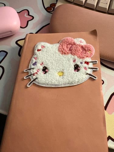 Customer's fluffy Hello Kitty embroidered sticker on a pink notebook cover.