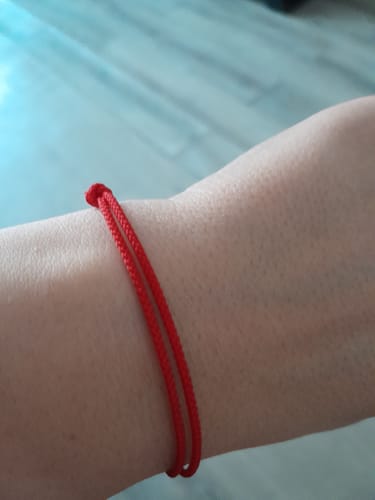 Gros plan du bracelet porte-bonheur 'Tibétain' rouge porté au poignet d'un client.