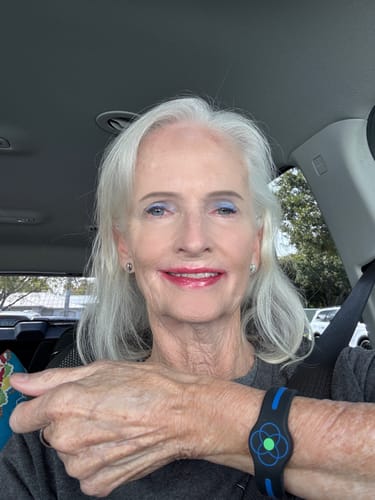 Customer smiling while showing the black and blue Ultimate Wellness Band on their wrist.