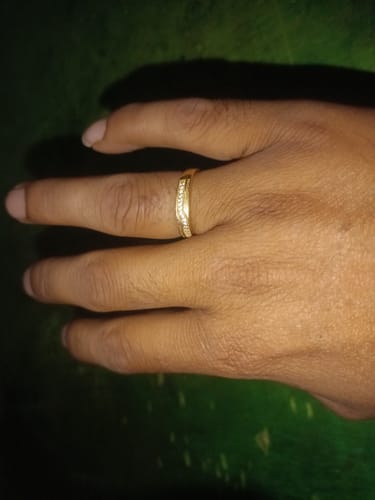 Customer's hand wearing the Golden Prominence Ring, showing the zircon-studded band against a dark background.