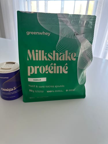 Photo d'un client montrant le sachet vert de Milkshake protéiné saveur vanille sur une table.