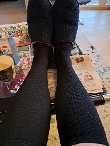 Recensent som har på sig svarta Diasocks stödstrumpor och vilar med fötterna upplagda på ett bord.