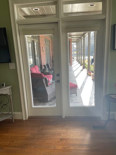 Reviewer's two white doors with new Clear 1 Lite Glass and Frame Kits installed, showing a clear view of a covered porch.