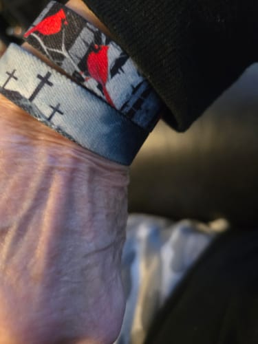 Customer's review photo showing two bracelets on a wrist, one with red cardinals and the other with crosses.