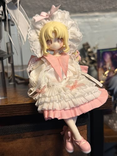 Reviewer's Meki Aipo action figure sitting on a shelf, fully dressed in her ruffled white and pink outfit.