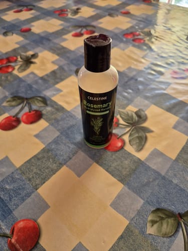 Customer's bottle of Rosemary and Keratin Shampoo standing on a patterned table.