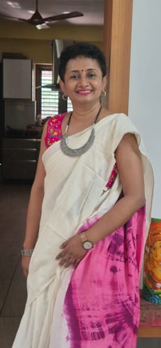 Customer wearing the pink sleeveless Kantha Raag designer blouse, styled with a white and pink saree in a home setting.