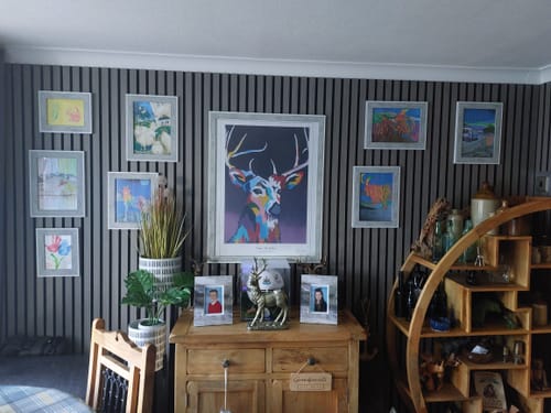 Customer's dark Slat Wall Panels installed as a feature wall, decorated with multiple framed pictures.