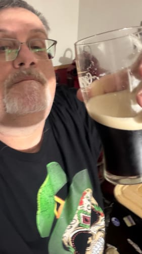 Customer wearing the black Irish I Was Mexican Calacas Tee while holding up a dark beverage.