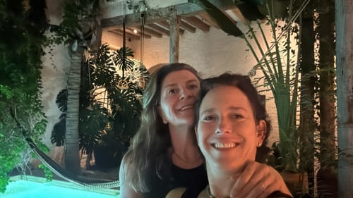 Customer reviewing Magnali Fuel, smiling with a friend in a nighttime outdoor setting by a pool.