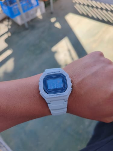 Cliente mostrando su reloj Casio Vintage W-218H-8BV de color claro en la muñeca al aire libre.