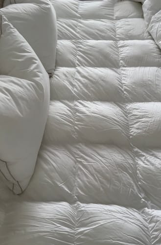 Customer's close-up of a white Hotel Cloud Collection™ pillow on a fluffy quilted comforter.